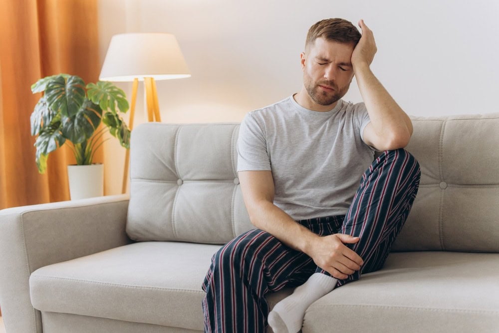 Tired man with weed hangover the next day showing fatigue and brain fog symptoms