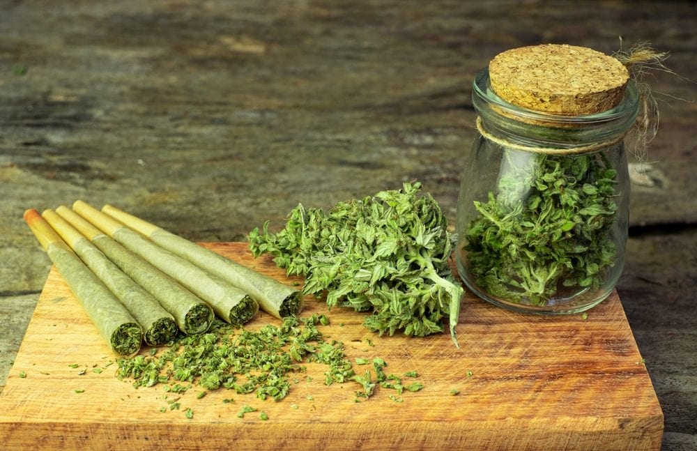 Pre-rolled joints and dried buds on a wooden board, a common way to use cannabis flower